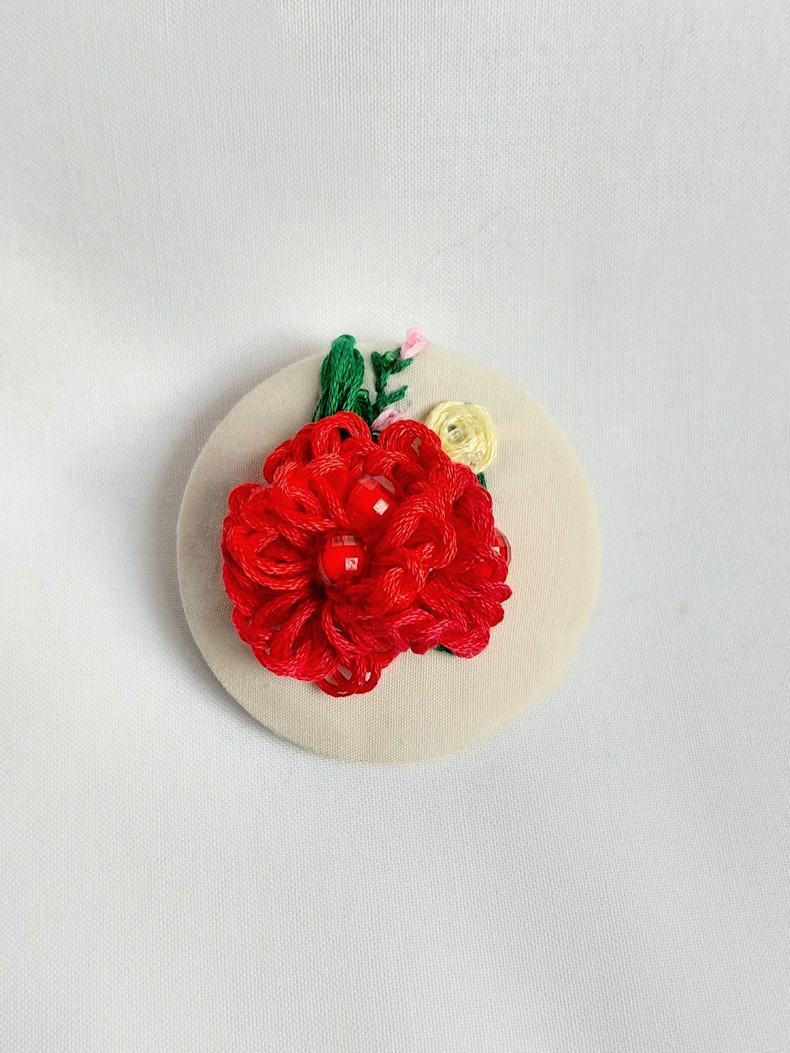 Decorative red flower brooch on cream background