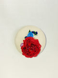 Decorative red flower brooch on cream background