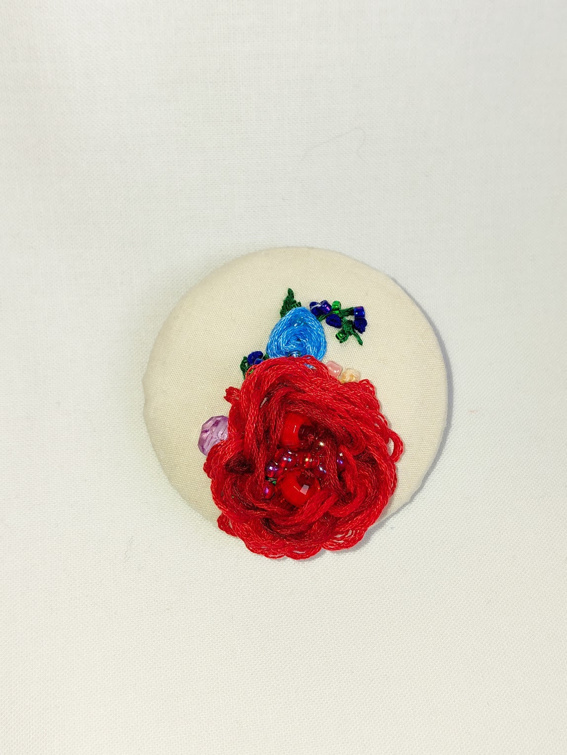 Decorative red flower brooch on cream background