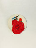 Decorative red flower brooch on cream background