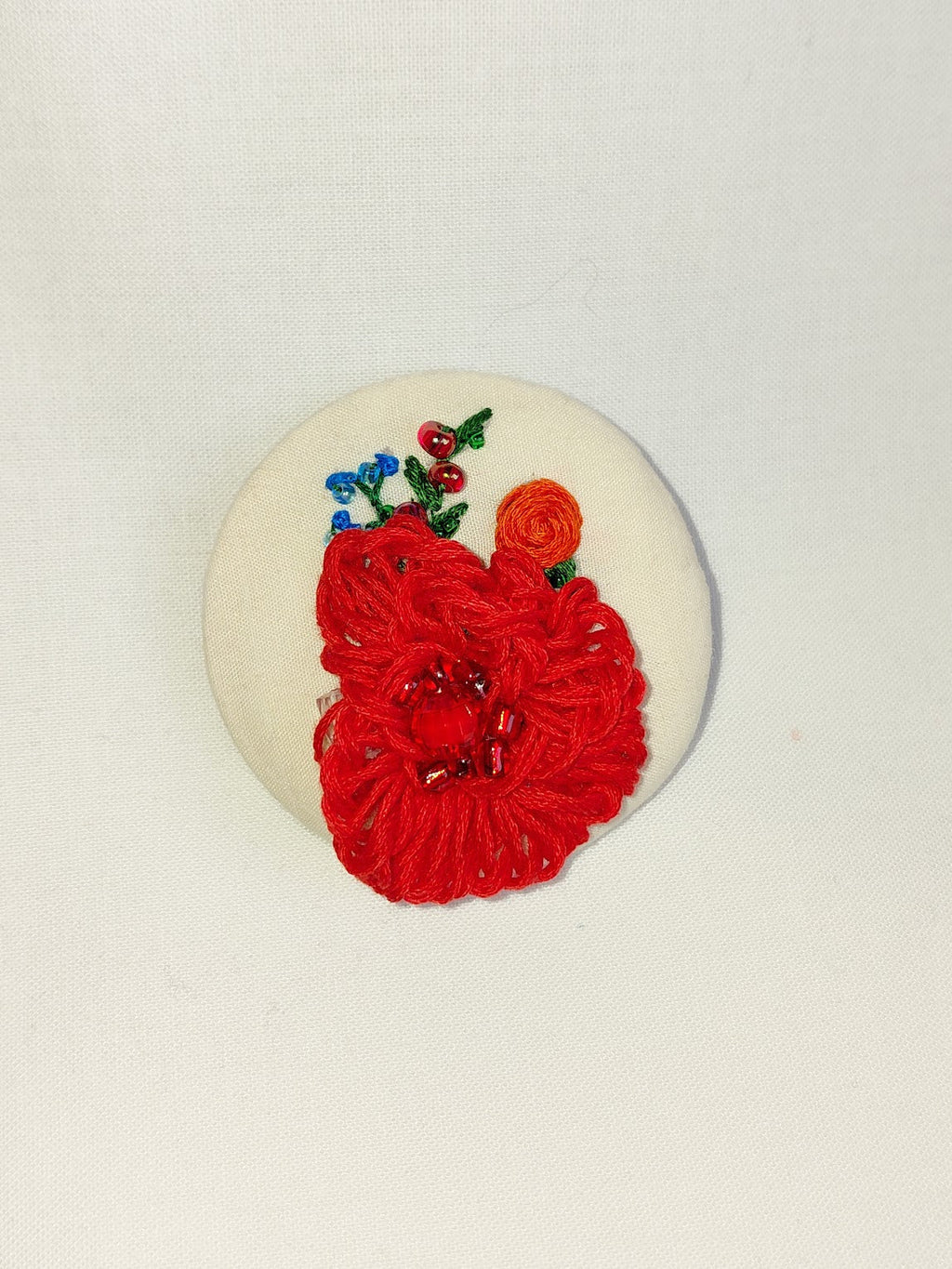 Decorative red flower brooch on cream background