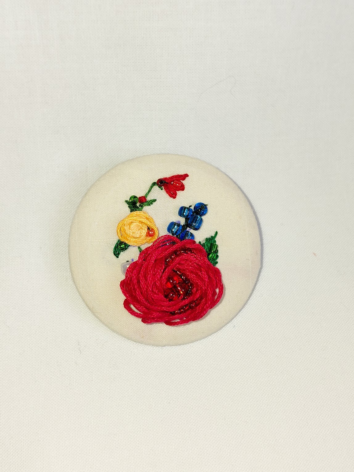 Decorative red flower brooch on cream background
