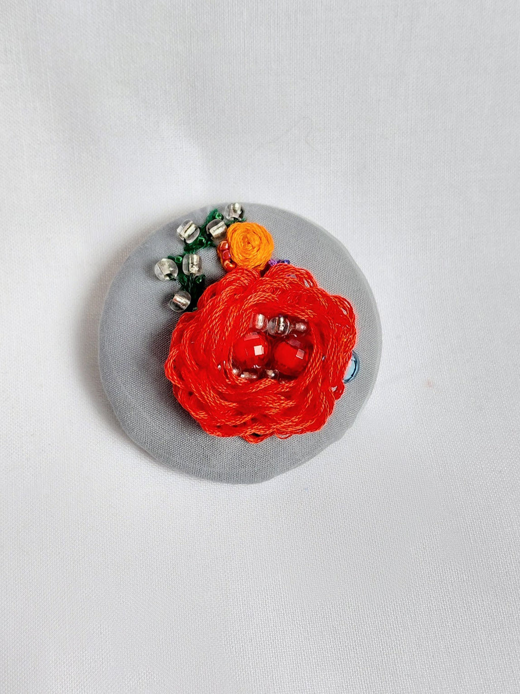 Decorative red flower brooch on grey background