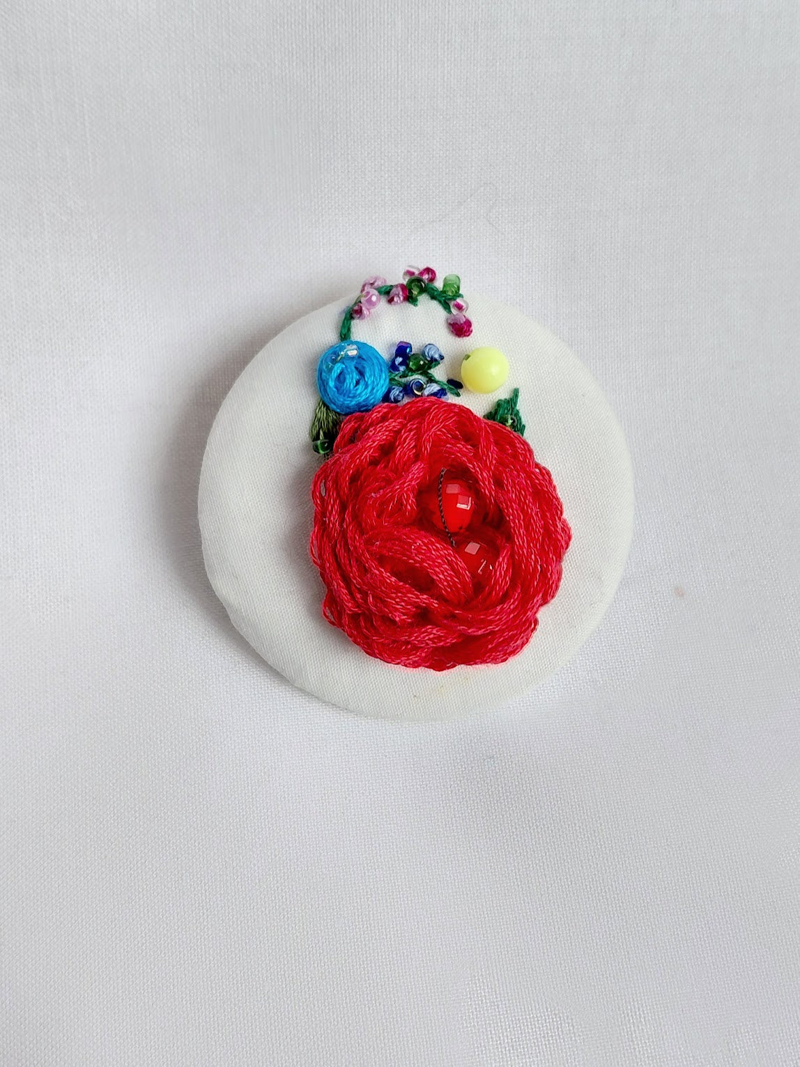 Decorative red flower brooch on white background