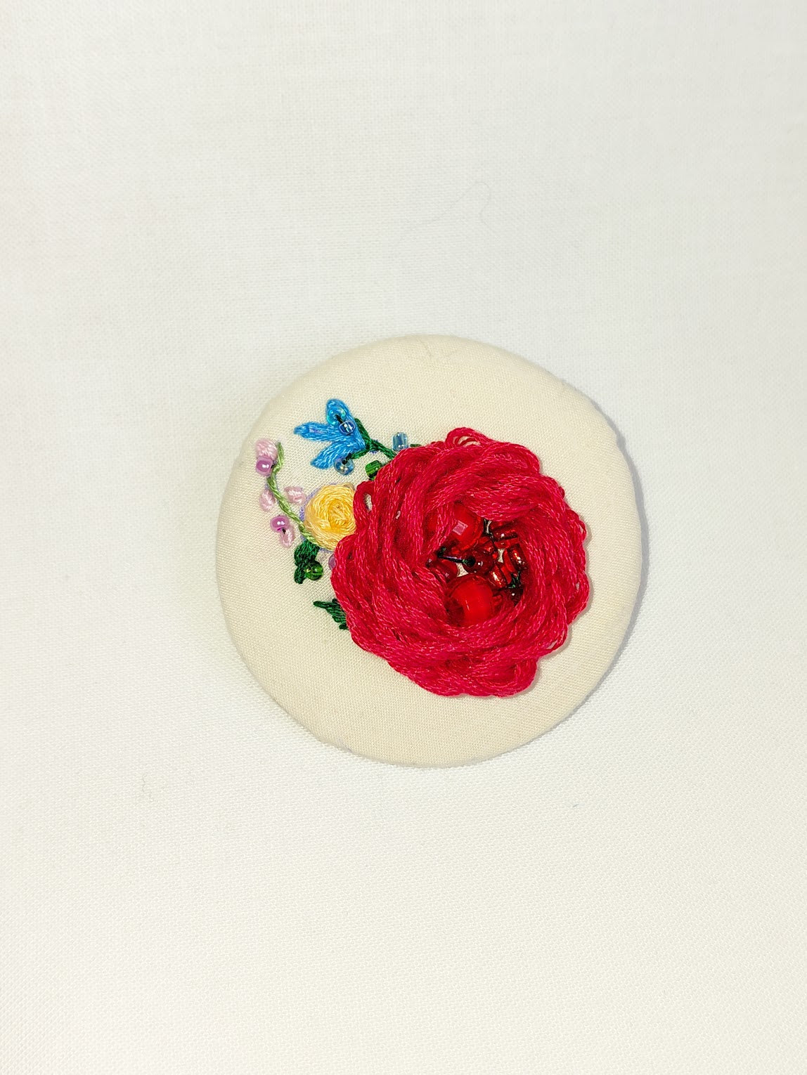 Decorative red flower brooch on cream background