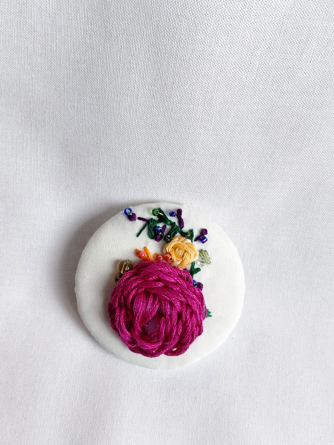 Decorative fuschia flower brooch on white background