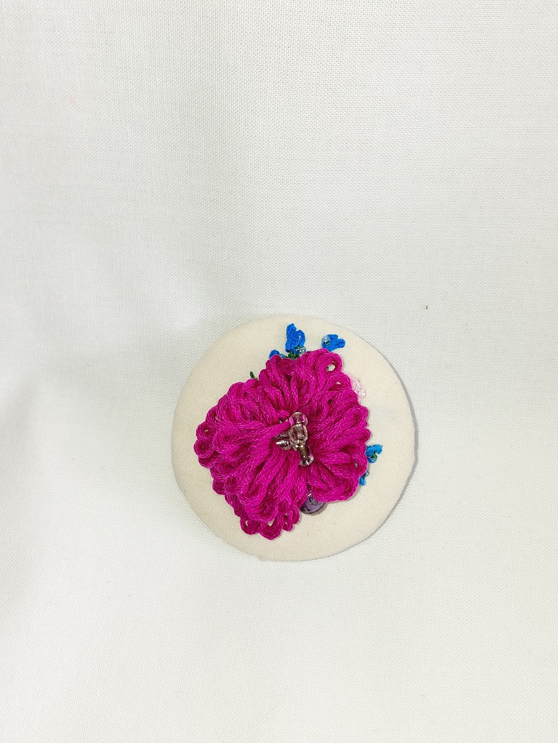 Decorative fuschia flower brooch on cream background