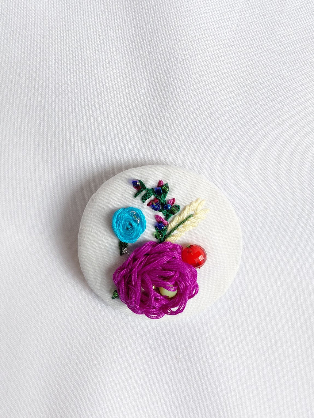 Decorative fuschia flower brooch on white background