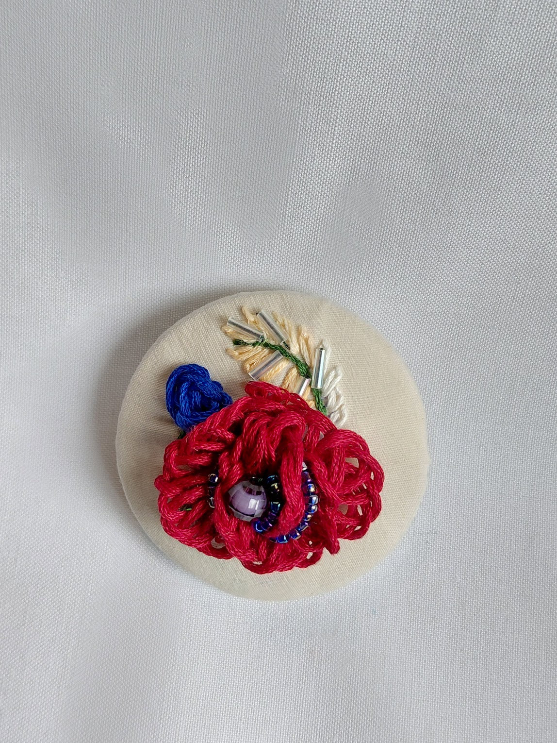 Decorative fuschia flower brooch on cream background