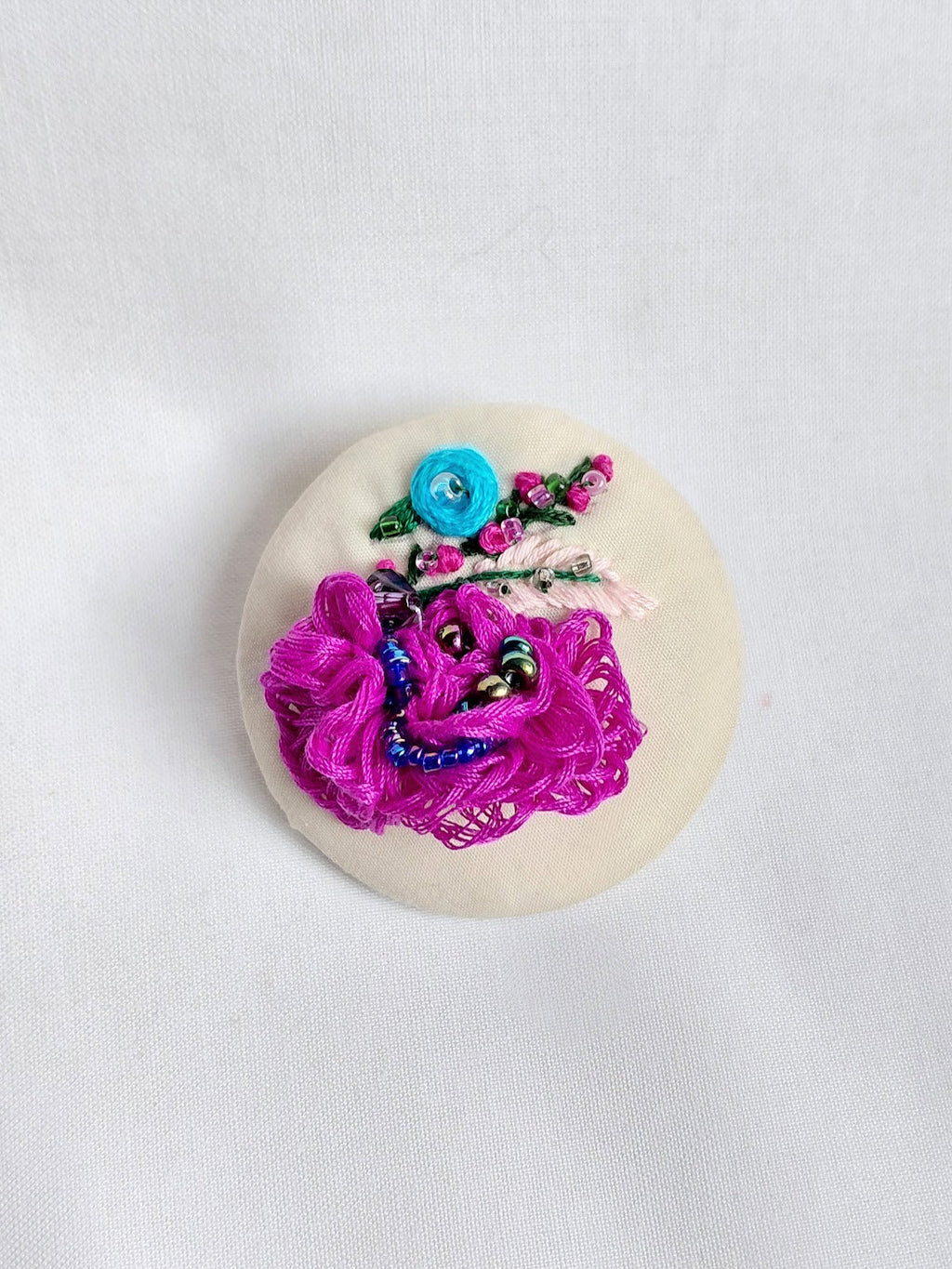 Decorative fuschia flower brooch on cream background
