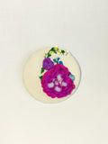 Decorative fuschia flower brooch on cream background