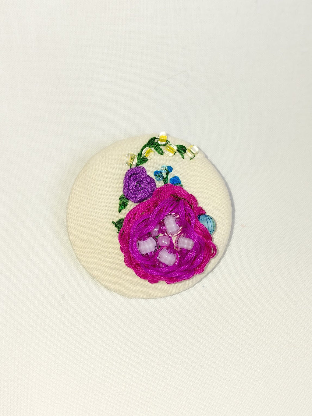 Decorative fuschia flower brooch on cream background