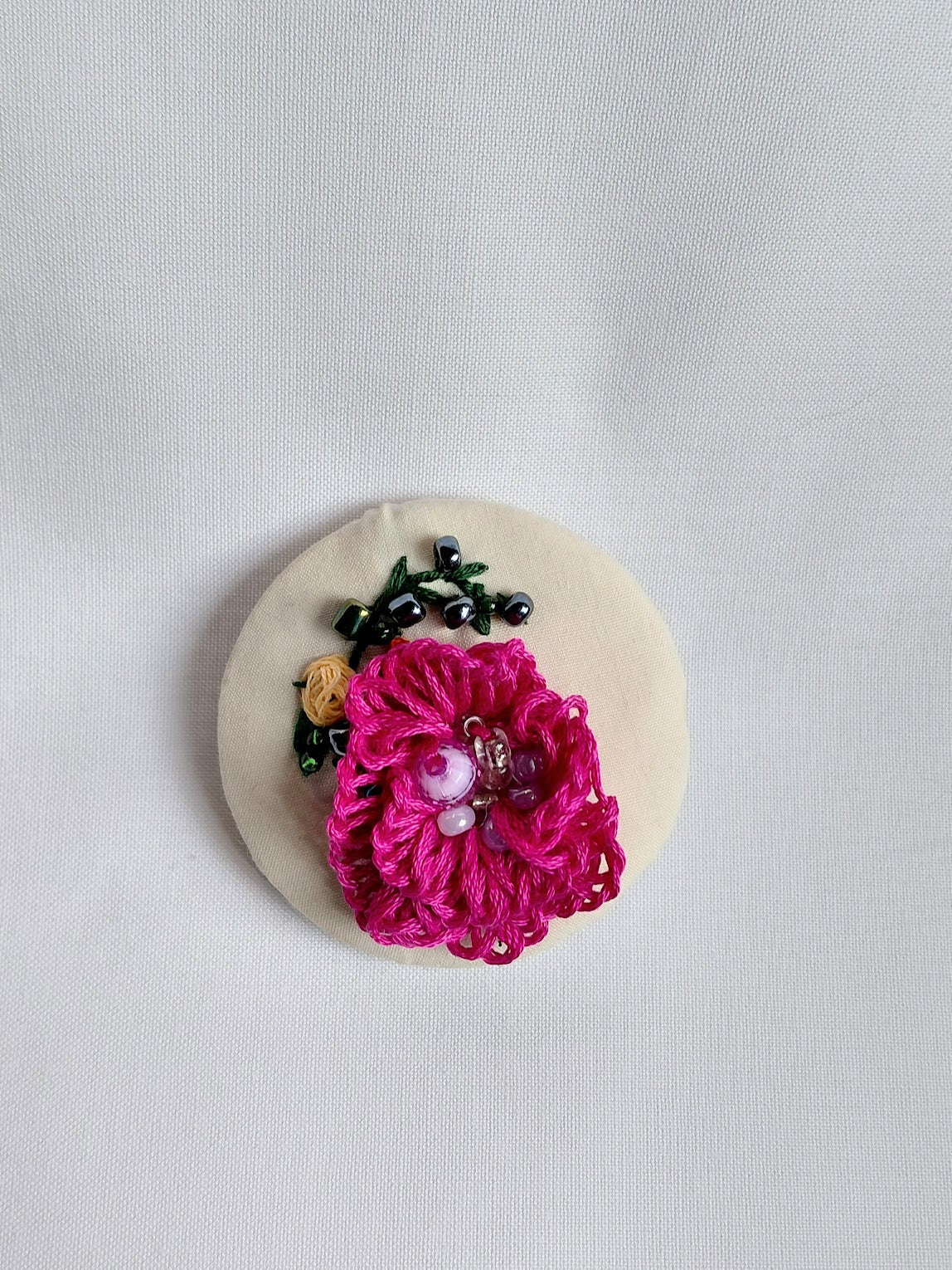 Decorative fuschia flower brooch on cream background
